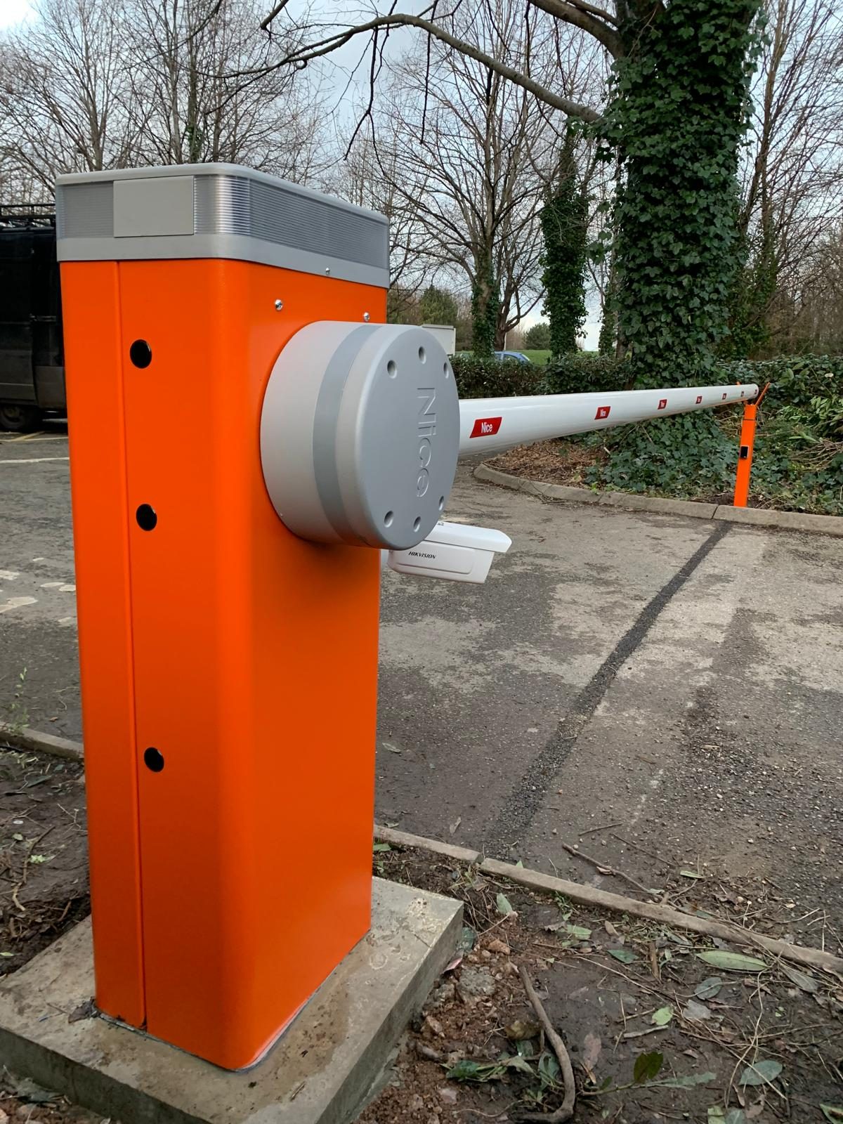 Orange Nice barrier cabinet with a Hikvision reader mounted on it and the boom extended across a car park entrance