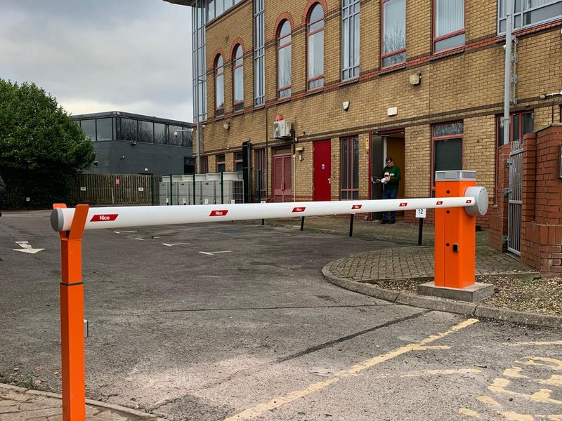 Nice automatic barrier lowered across a business park entrance in front of a brick office building