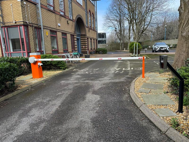 Nice automatic barrier across the entrance road to an office building, with a card reader on a post beside it